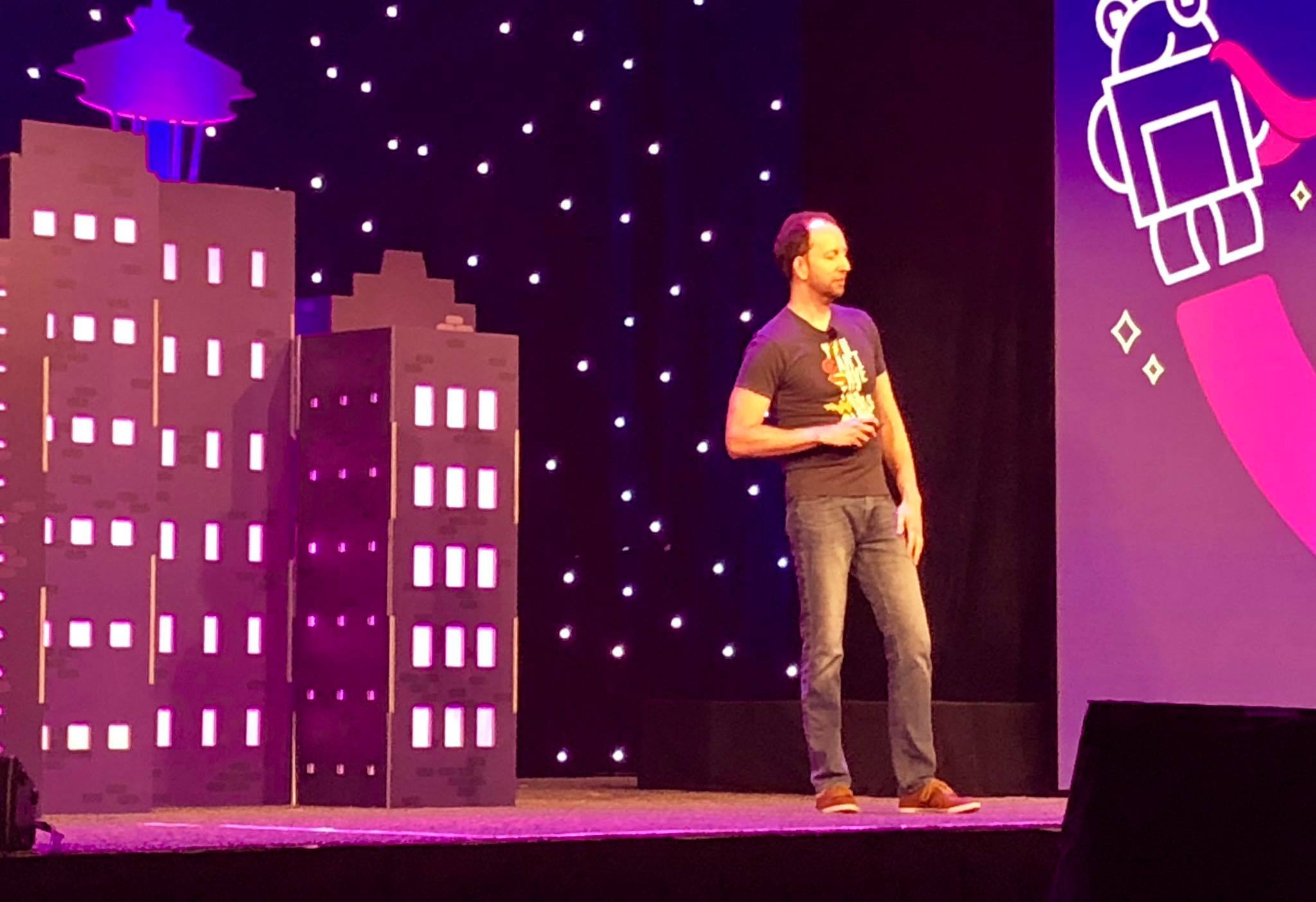 Dr. Pete Meyers on the MozCon stage, mid-session, the city skyline set piece behind him.